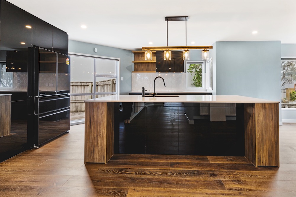 Modern kitchen interior featuring dark wood cabinets, an island, stainless steel appliances, and pendant lights above the island.
